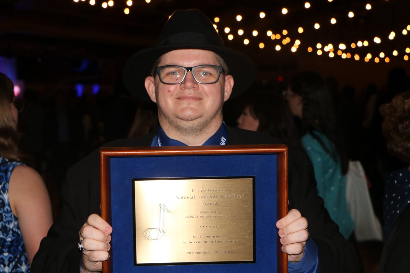 An Alpha Psi brother holding the F. Lee Bowling award plaque