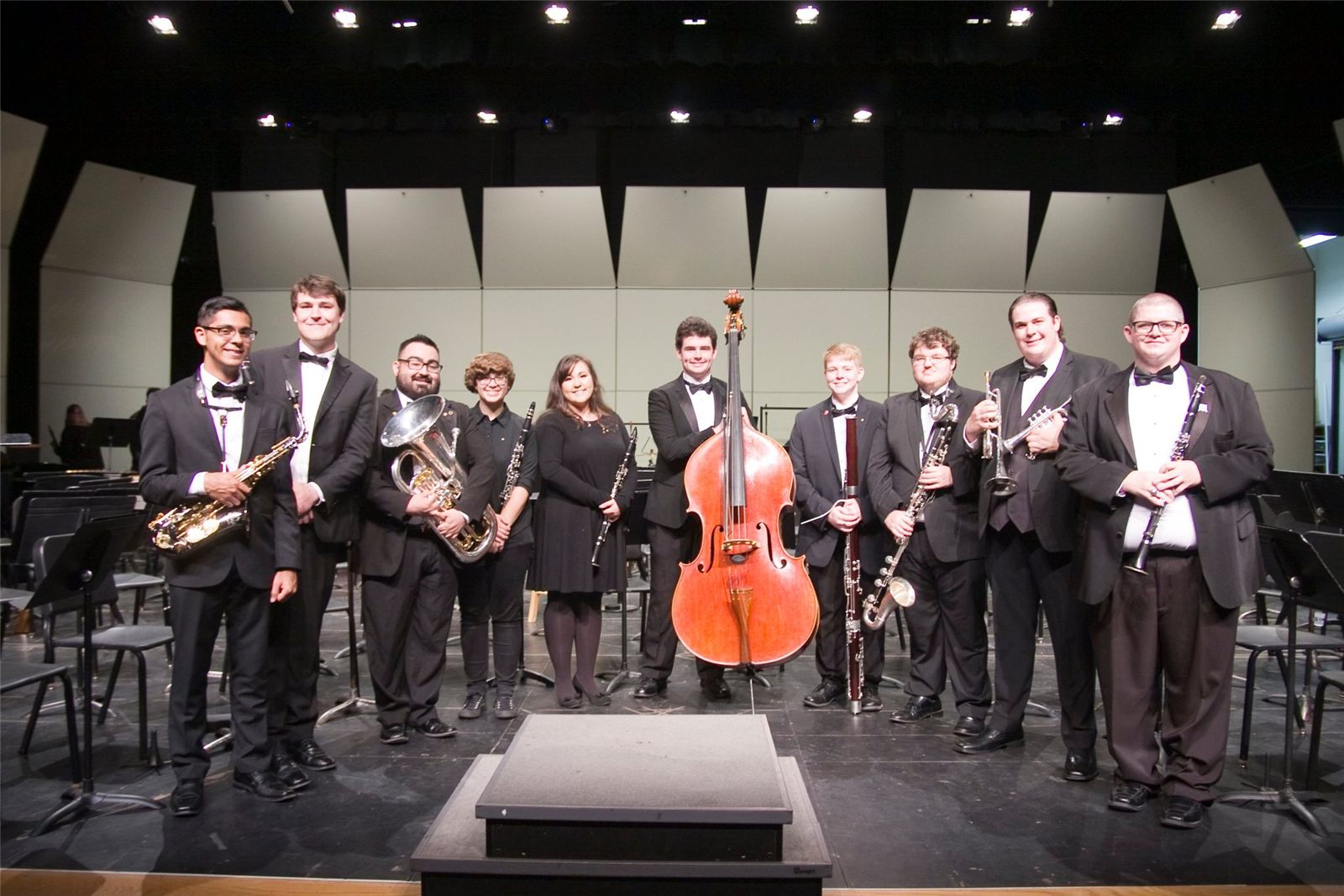 Eleven musicians in concert black holding their instruments on stage