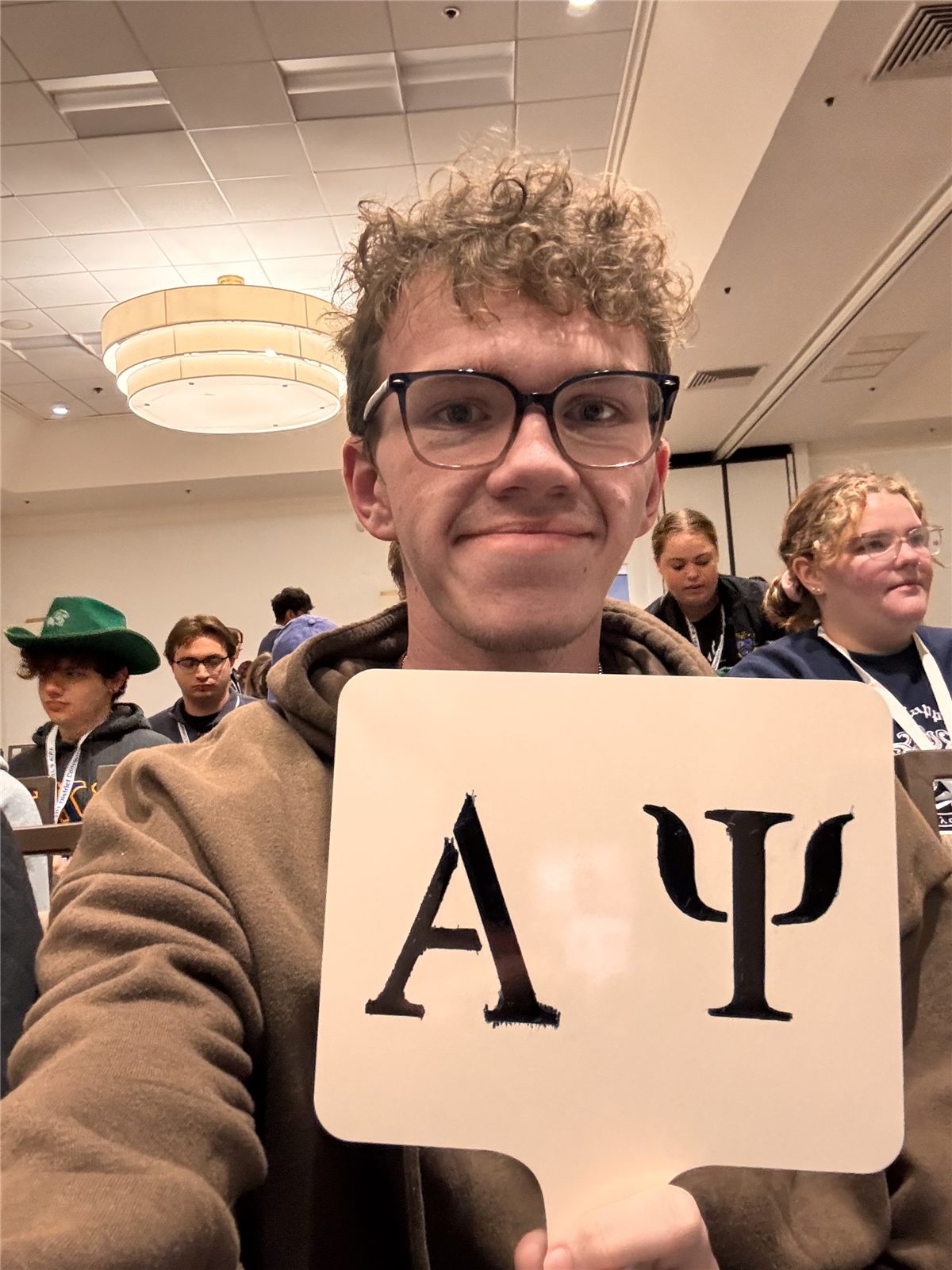 Fisher Boone holding an Alpha Psi voting paddle at convention