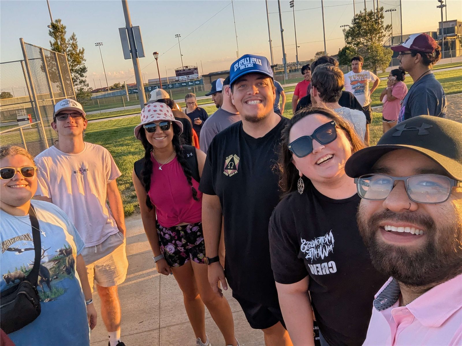 A smiling group of brothers taking a selfie outside at sunset